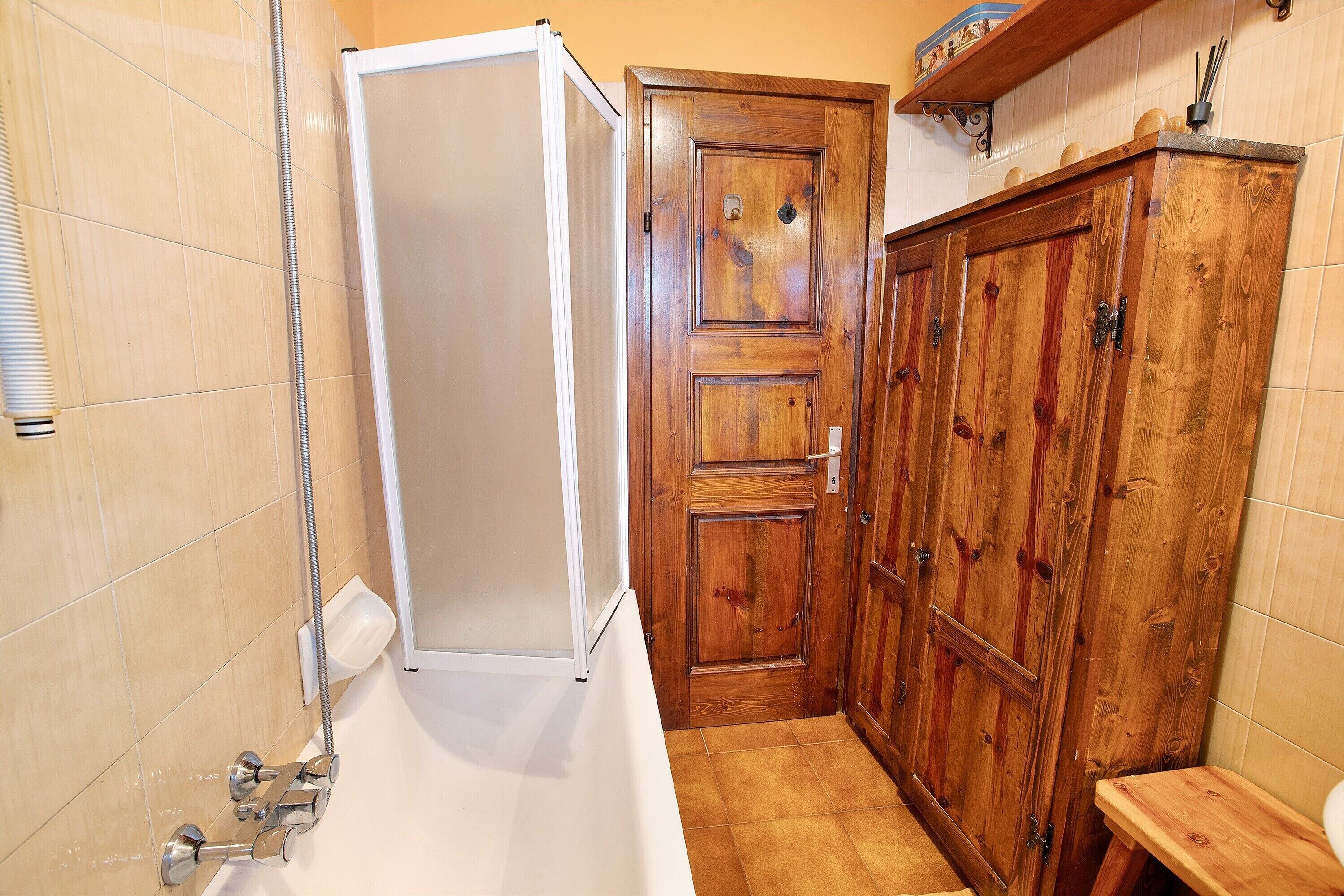 A bathroom with a shower, wooden cabinets, and a toilet.