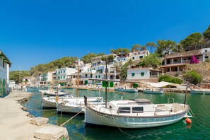 A coastal village with boats docked at a pier, traditional buildings, and a clear blue sky.