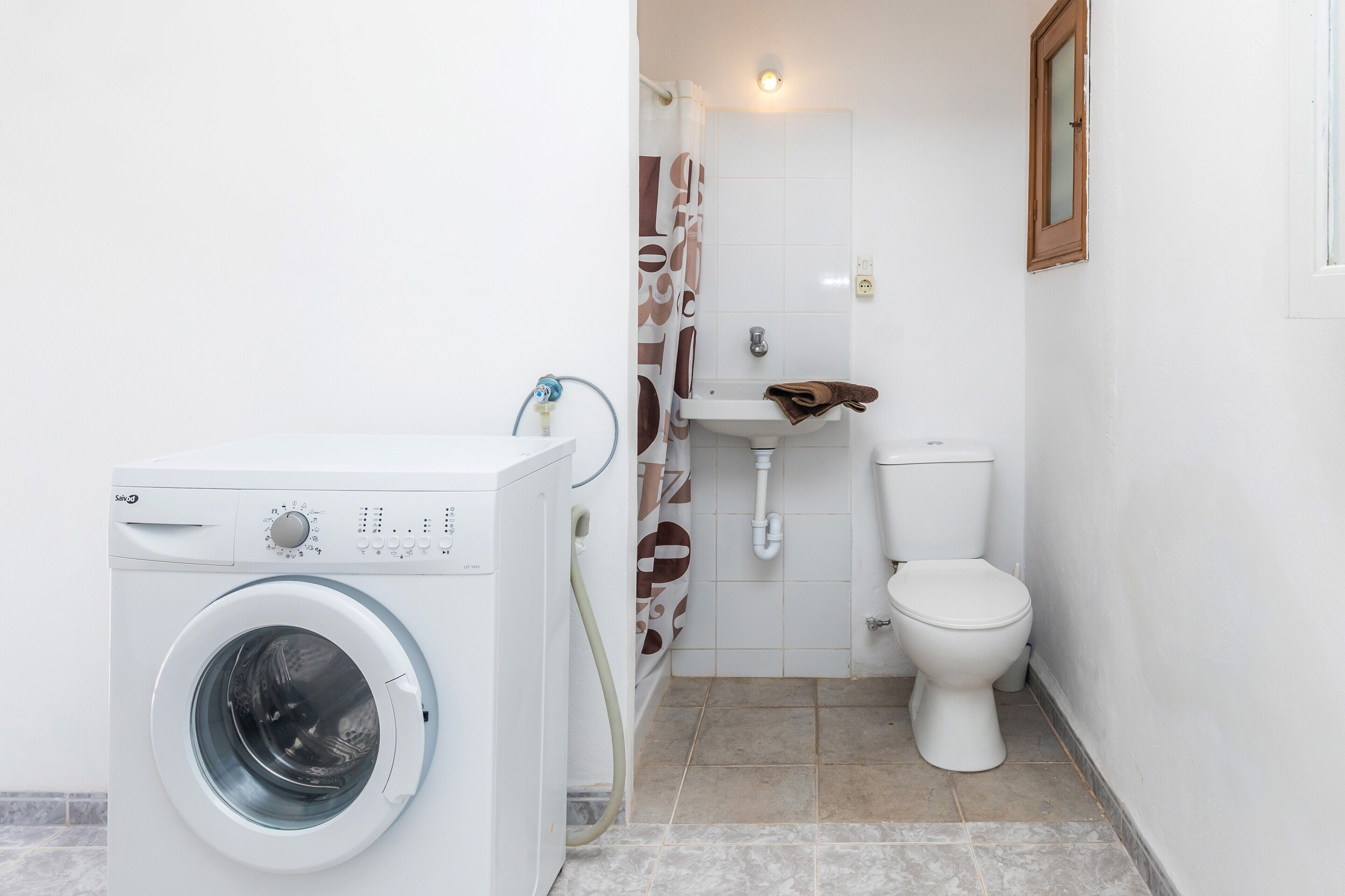 Un baño pequeño con lavadora, lavamanos e inodoro.