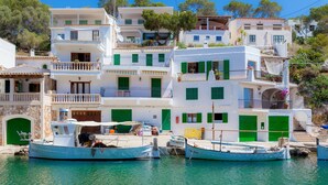 A coastal building with multiple balconies, a boat docked in front, and a clear blue sky.