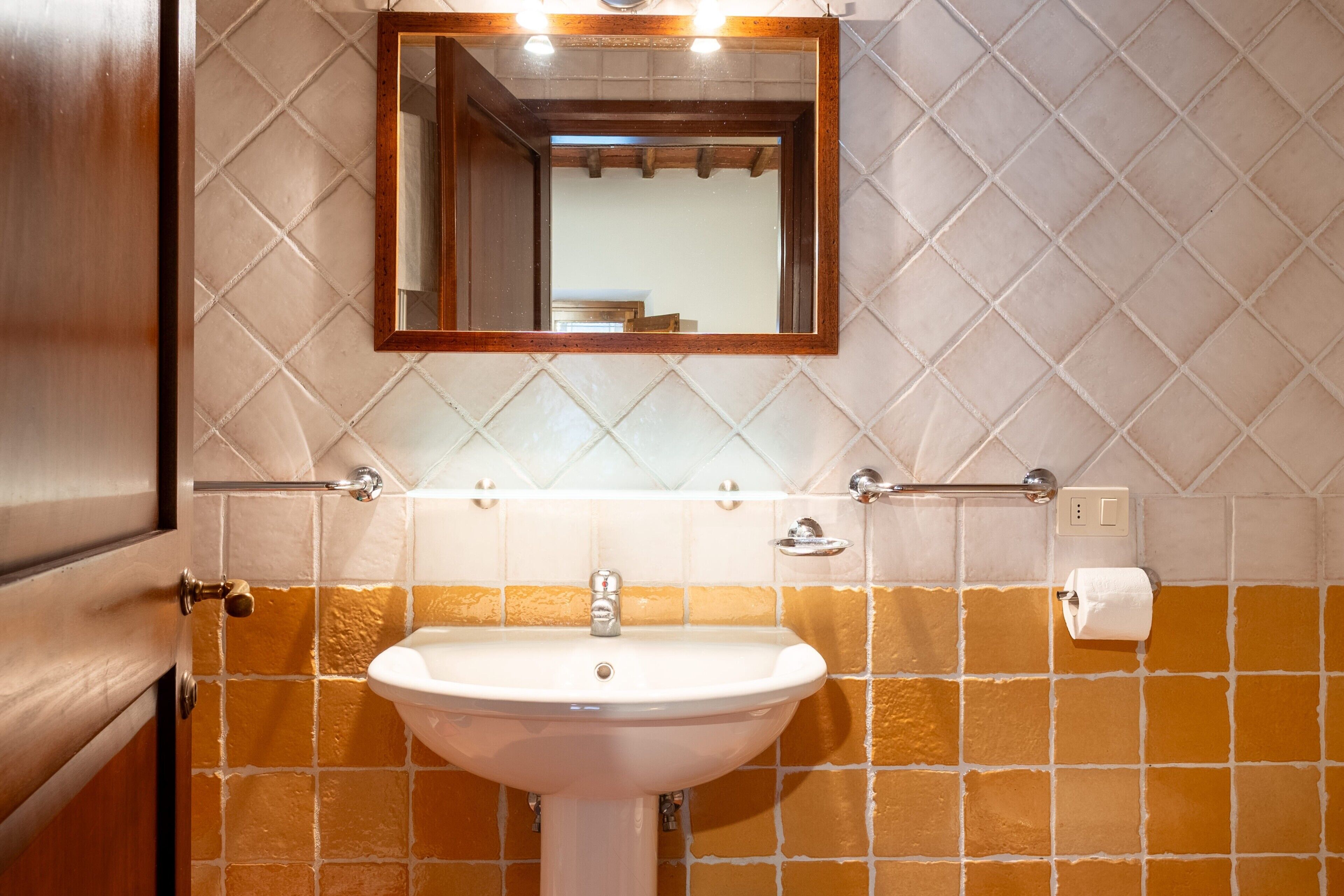 Un baño con un lavamanos blanco, un espejo y un toallero.