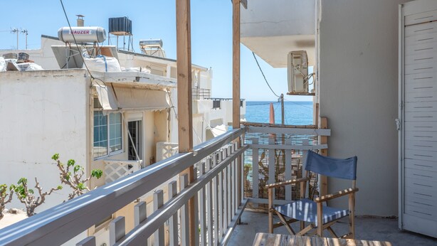 Ein Balkon mit Stuhl, Geländer und Meerblick.