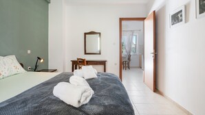 Ein Schlafzimmer mit Bett, Schreibtisch, Stuhl, Spiegel und einer Tür, die auf einen Balkon führt.
