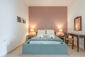 Una camera da letto con un letto, due lampade ai comodini, una scrivania, una sedia e due quadri appesi al muro.