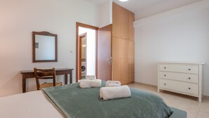 Une chambre à coucher comprenant un lit, un bureau, une chaise, une armoire et une commode.