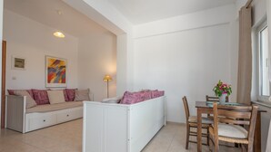 Un salon avec un canapé, une table à manger et des chaises, un radiateur et un tableau accroché au mur.