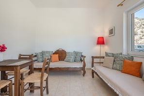 A room with a wooden sofa, a wooden table, and a red floor lamp. - Holiday Apartment "Standard" with Sea View, 2 Shared Terraces & Wi-Fi (Crete)