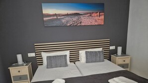Un lit double avec deux oreillers, une tête de lit, des tables de chevet avec des lampes et un tableau au-dessus.