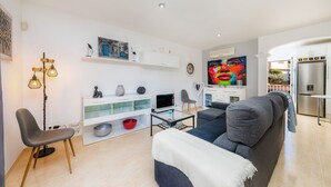 Un salon moderne comprenant un canapé, un téléviseur et un coin repas avec un réfrigérateur.