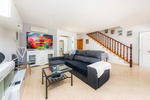A living room with a sofa, coffee table, TV, and a staircase.