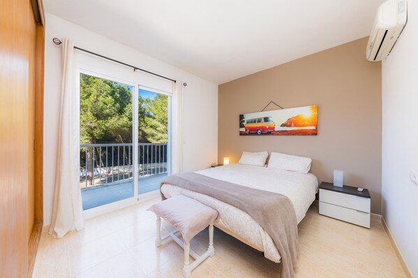 Une chambre à coucher comprenant un lit, un banc, une table de chevet et un tableau représentant un camion.