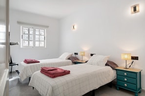 Une chambre avec deux lits, une table de chevet avec une lampe, une fenêtre donnant sur un beau paysage et une porte.