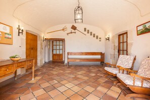 A room with a wooden bench, a wooden table, a tiled floor, and a wall-mounted light fixture. - Holiday Home 'El Cup' with Mountain View, Shared Pool and Wi-Fi (Sant Marti de Tous)