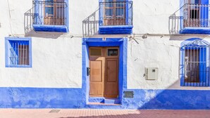 A building with a blue and white facade, a wooden door, and a small balcony with a metal railing. - Holiday Home 'La Clau Casa Rural ' with Mountain View, Private Terrace and Wi-Fi (Polop)