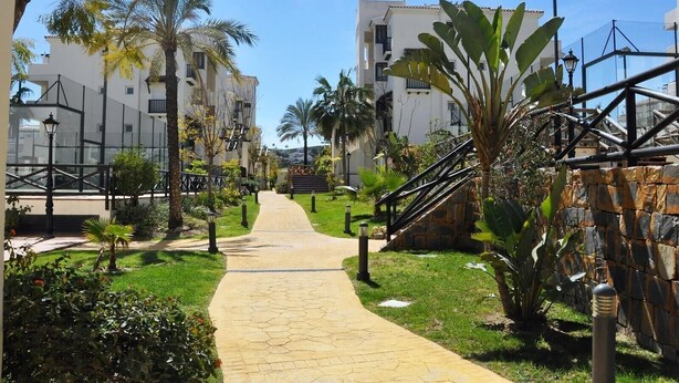 A pathway leading to a building with a staircase, surrounded by greenery and palm trees. - Apartment 'Residencial Duquesa Fase I' with Terraces, Shared Pools & Wi-Fi (Manilva)