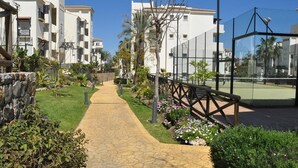 A pathway leading to a building with a stone wall on one side and a fence on the other. - Apartment 'Residencial Duquesa Fase I' with Terraces, Shared Pools & Wi-Fi (Manilva)