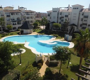 Una piscina rodeada de vegetación y edificios residenciales.