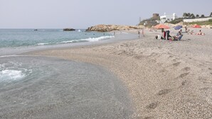 A pebbly beach with clear water, umbrellas, and people. - Apartment 'Residencial Duquesa Fase I' with Terraces, Shared Pools & Wi-Fi (Manilva)