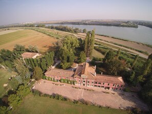 An aerial view of a large, historic building with multiple wings, surrounded by expansive fields and a river in the background. - 'Tenuta Ca' Zen - Cottage Casetta' with Shared Pool, Wi-Fi and Air Conditioning (Taglio di Po)