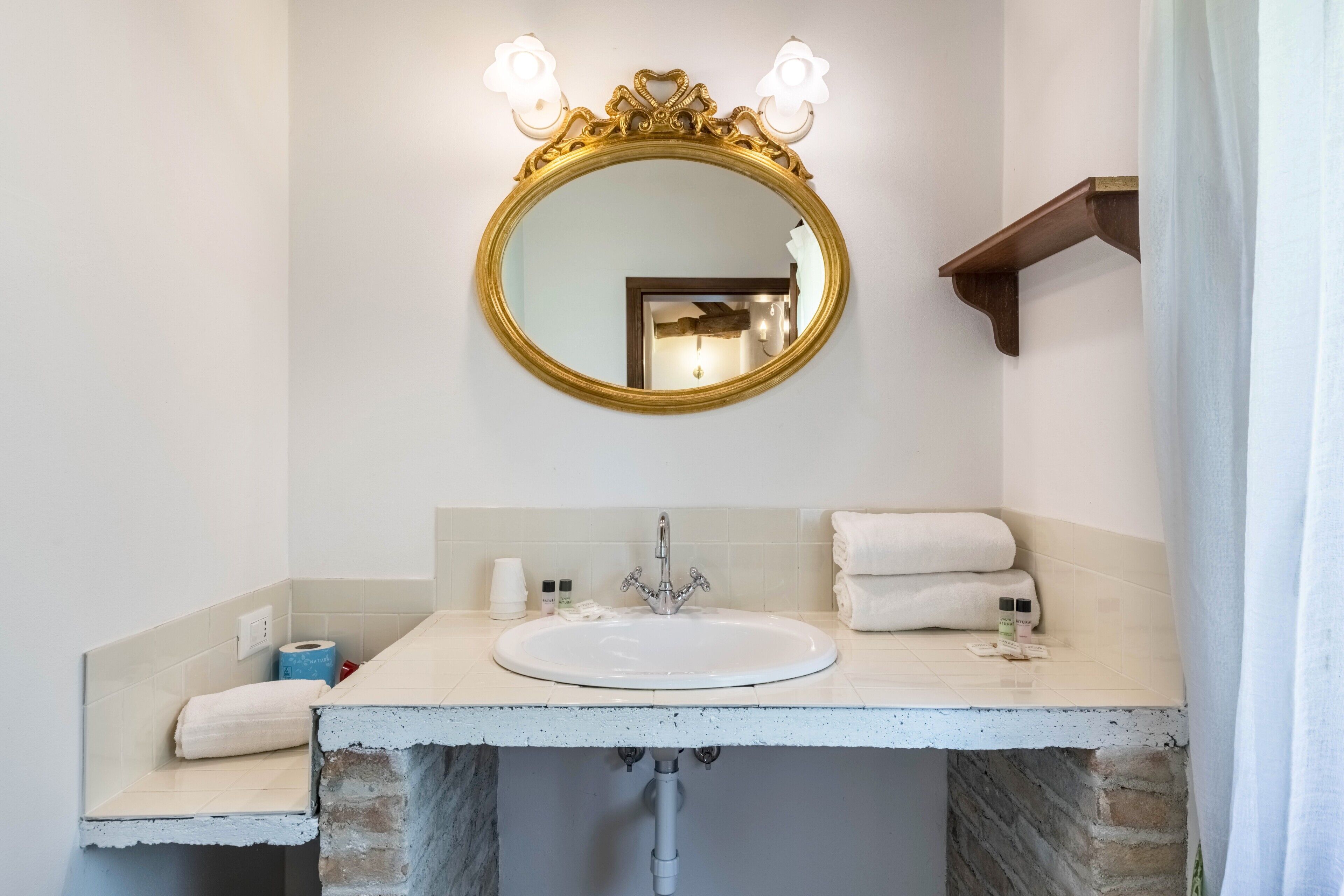 A bathroom with a round mirror, a sink, and a towel rack.