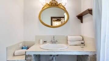 A bathroom with a round mirror, a sink, and a towel rack.