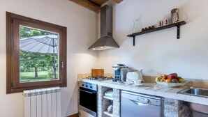 Une cuisine avec une fenêtre, une cuisinière, un lave-vaisselle et un panier à fruits.