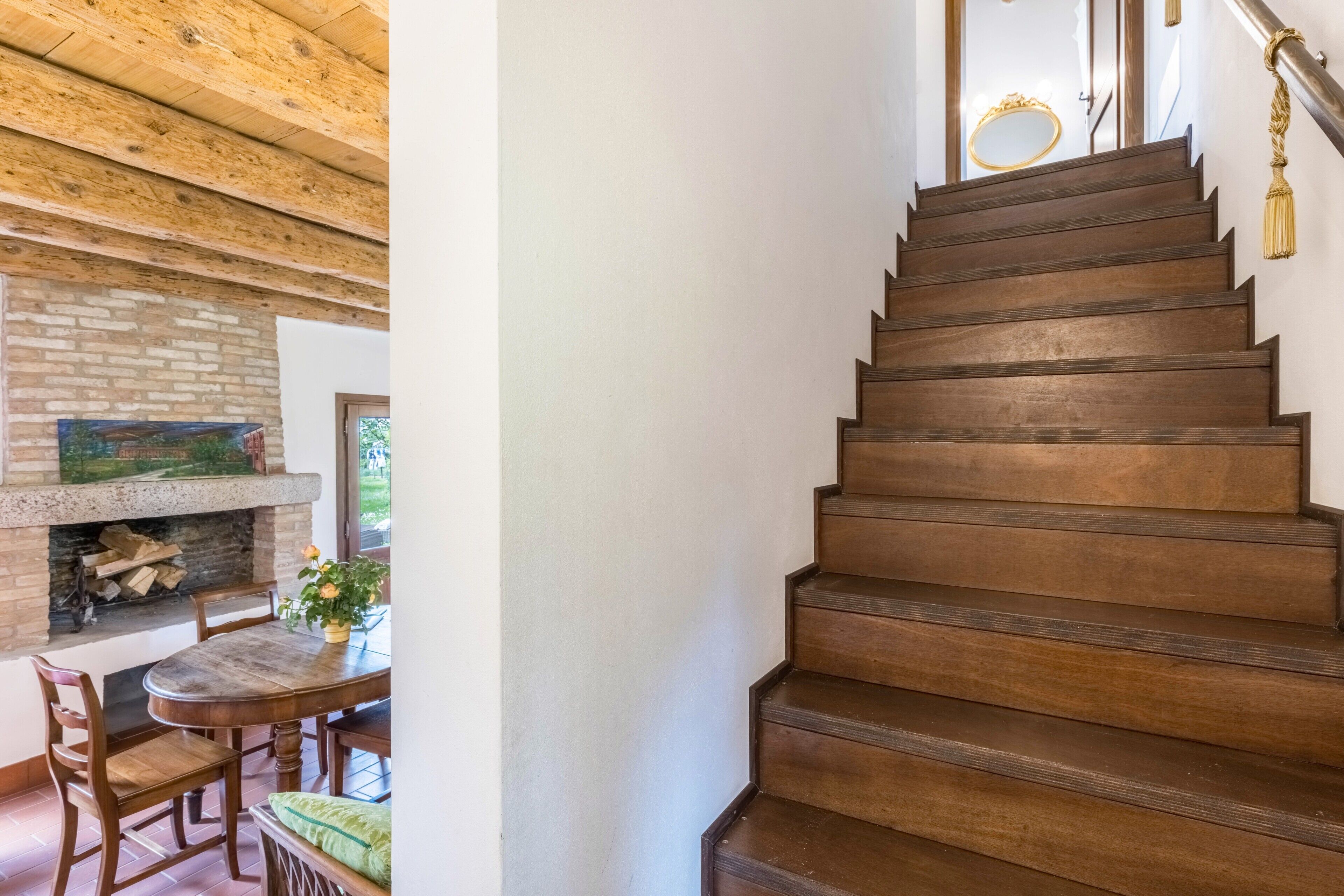 Eine Holztreppe mit Handlauf und einem dekorativen Spiegel am Obergeschoss.