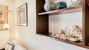 Une pièce avec une étagère en bois où sont exposés des objets décoratifs, un tableau encadré au mur et une lampe.