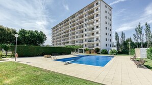 Un immeuble résidentiel à plusieurs étages doté d’une piscine, d’un espace extérieur aménagé et d’une pelouse bien entretenue.