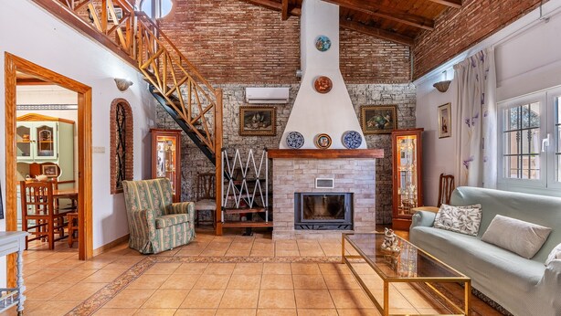 A spacious living area with a fireplace, wooden staircase, and a cozy seating arrangement. - Holiday Home 'Villa Verde' with Mountain View, Private Pool and Wi-Fi (Nigüelas)