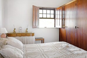 Une chambre à coucher avec un lit, une commode, une fenêtre et une armoire.