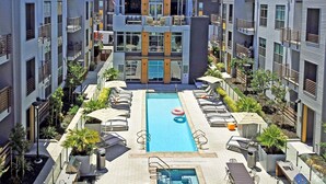 A modern hotel with a central pool, outdoor seating, and a view of the mountains. - Elan Menlo (Menlo Park)