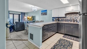 Une cuisine moderne avec des meubles gris, un îlot central et un pare-feu en carreaux.