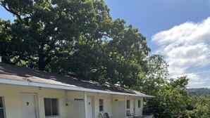 A motel with numbered rooms, outdoor seating, and a barbecue grill. - Resort 2bdrm condo on Table Rock Lake, by SDC! (Branson)