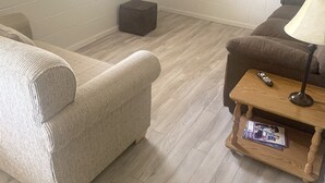 A living room with a beige sofa, a brown sofa, a wooden coffee table, and a television mounted on the wall. - Resort 2bdrm condo on Table Rock Lake, by SDC! (Branson)