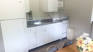 A kitchen with white cabinets, a sink, a stove, and a dining table with chairs. - Resort 2bdrm condo on Table Rock Lake, by SDC! (Branson)