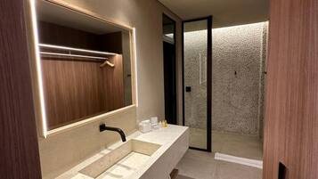 Un baño moderno con un espejo grande, lavamanos dobles y ducha a ras de suelo.