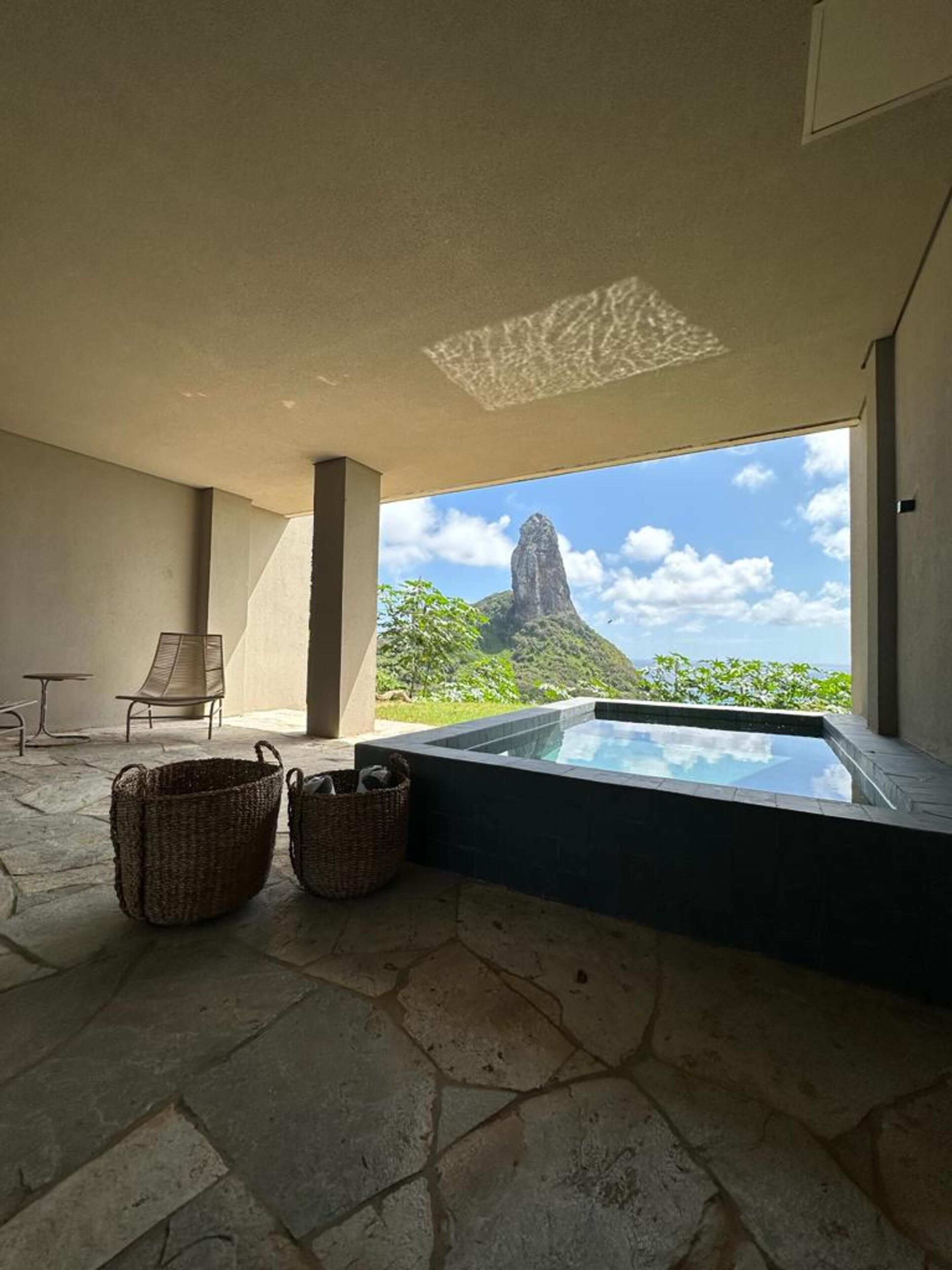 Un espace bien-être comprenant un jacuzzi, des paniers en osier et une vue sur la montagne.