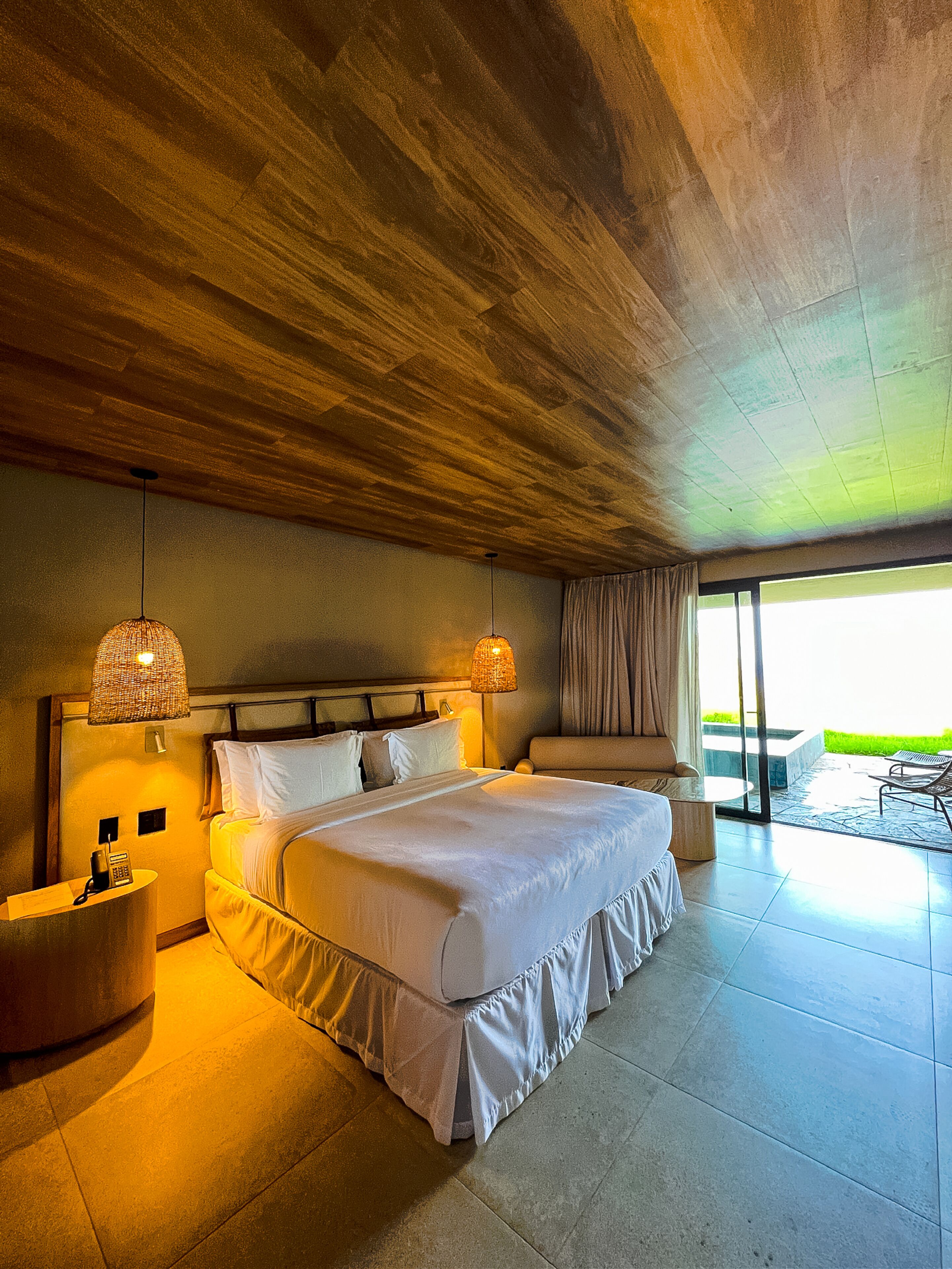 Un dormitorio amplio con una cama grande, lámparas de noche, una mesita de noche y vistas al exterior.