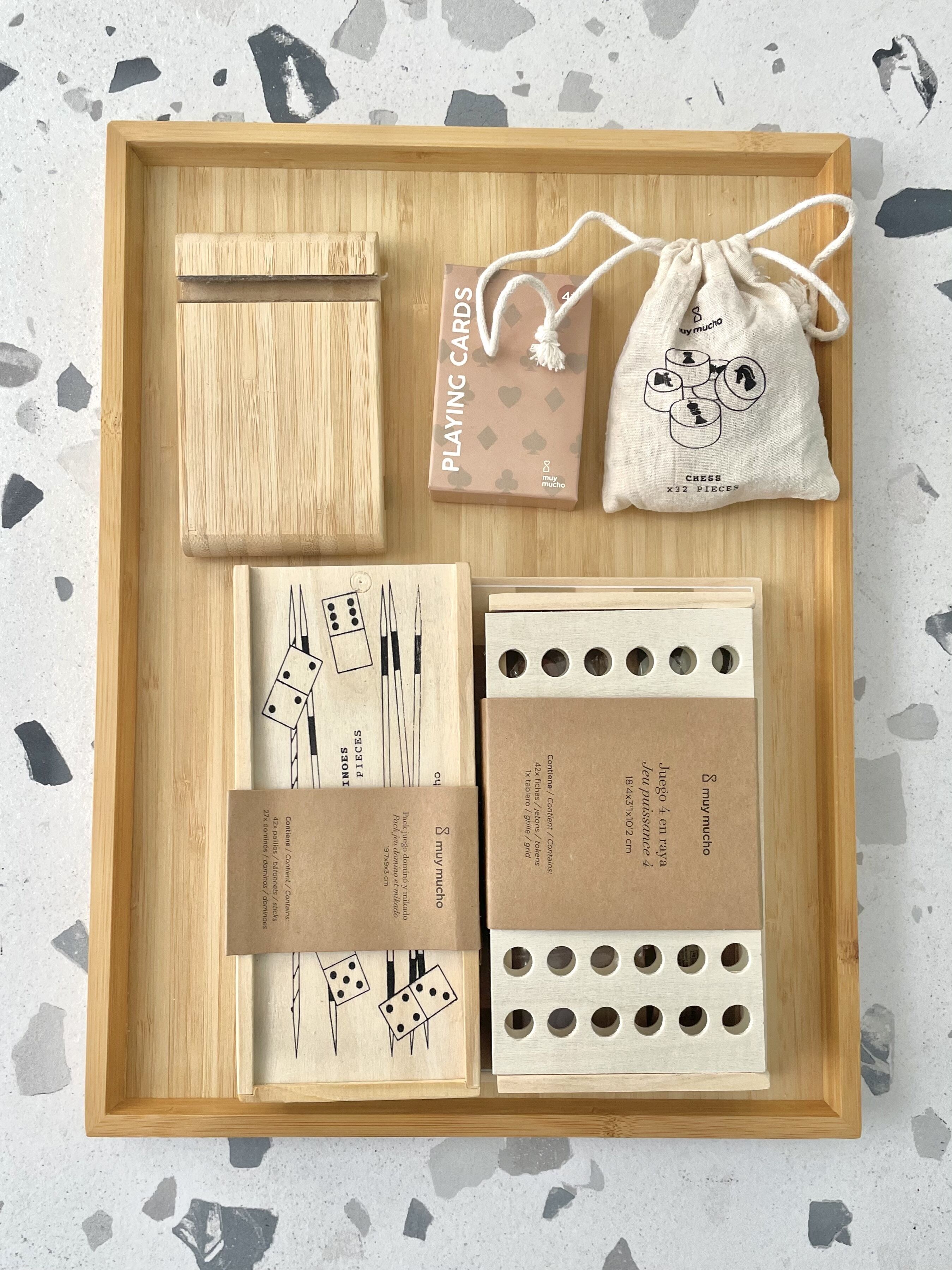 A wooden tray with a chess set, playing cards, a drawstring bag, and wooden dice.