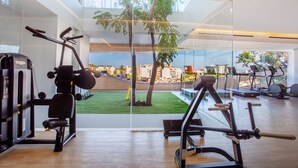 Une salle de sport moderne, dotée de divers appareils d’exercice, de grandes fenêtres et offrant une vue sur le paysage urbain.