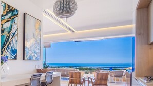 Un intérieur moderne avec un bar, des espaces pour s’asseoir et une vue sur l’océan.