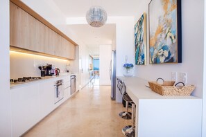 Een moderne keuken met een centraal eiland, roestvrijstalen apparatuur en uitzicht op een eetgedeelte.