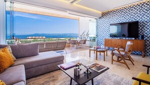 Un salon moderne doté d’un grand téléviseur, de sièges confortables et offrant une vue sur la mer.
