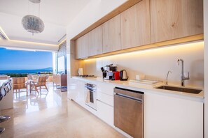 Een moderne keuken met uitzicht op zee, voorzien van een koffieapparaat, waterkoker en vaatwasser.