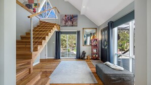 A spacious living area with a wooden staircase, a large window, and a cozy seating area.
