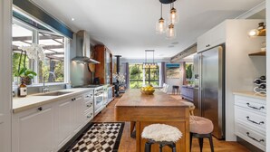 A modern kitchen with white cabinets, a wooden island, and a large window.