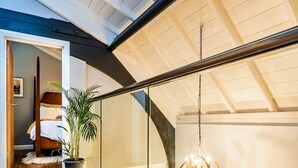 A modern interior with a wooden floor, a potted plant, and a hanging light fixture. - The Church Vaults (Matlock)