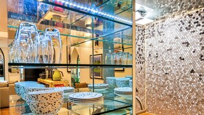 A kitchen with a glass display case filled with plates and bowls, a stainless steel sink, and a mosaic backsplash. - The Church Vaults (Matlock)