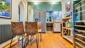 A modern kitchen with a refrigerator, microwave, and wooden shelves. - The Church Vaults (Matlock)